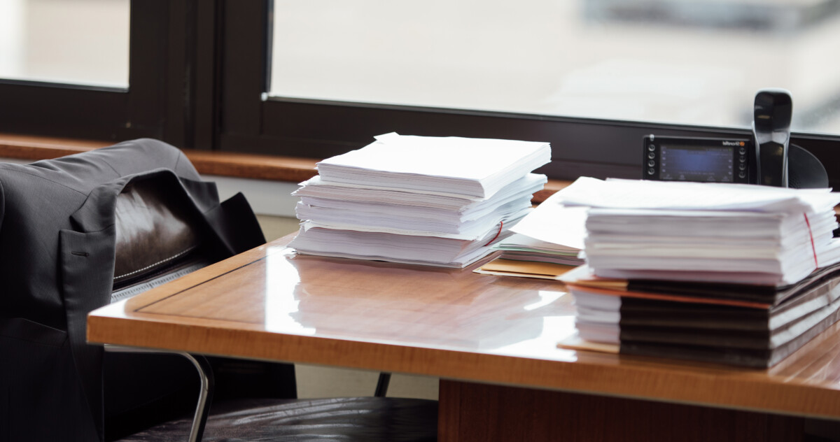 work desk with stacks of papers and contracts