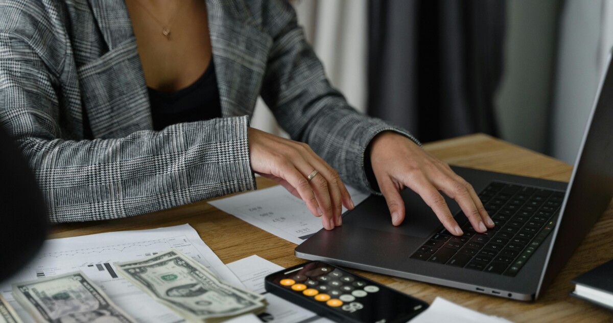Woman Using Laptop, Calculator, Cash for Financial Matters